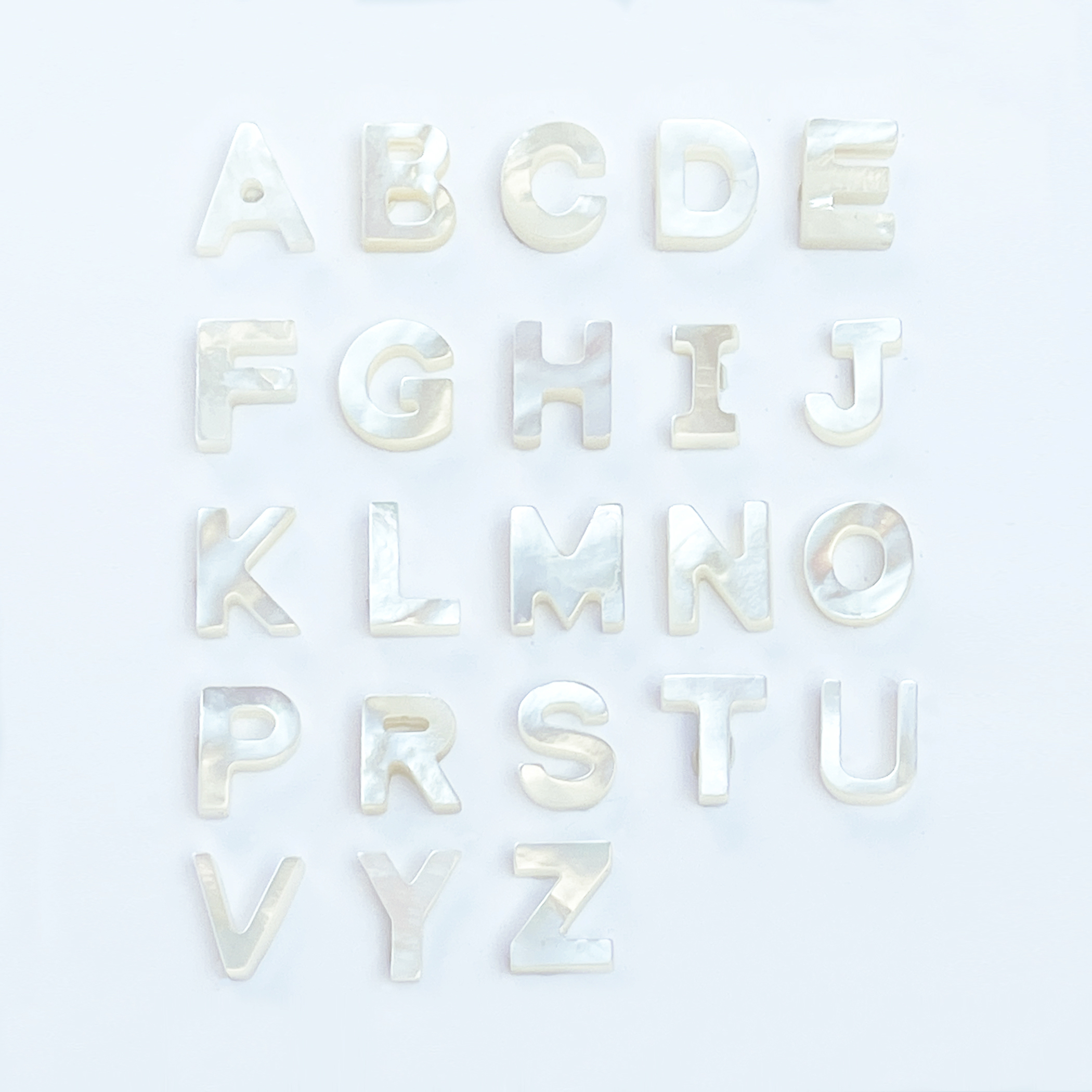 Lettera in Madreperla , colore Bianco, altezza 10 mm, larghezza variabile da 5 a 9 mm.